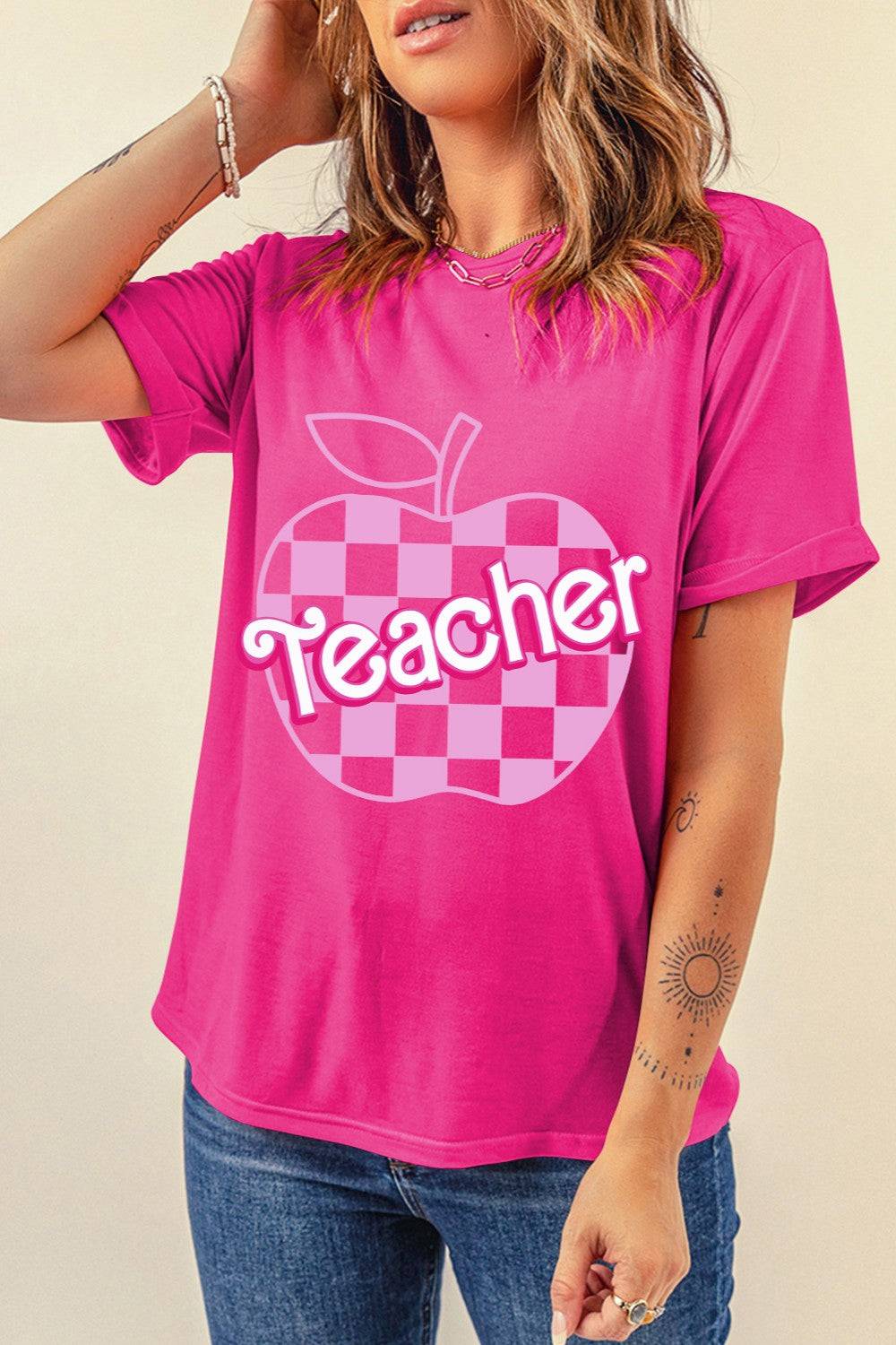 a woman wearing a pink shirt with a checkered apple on it