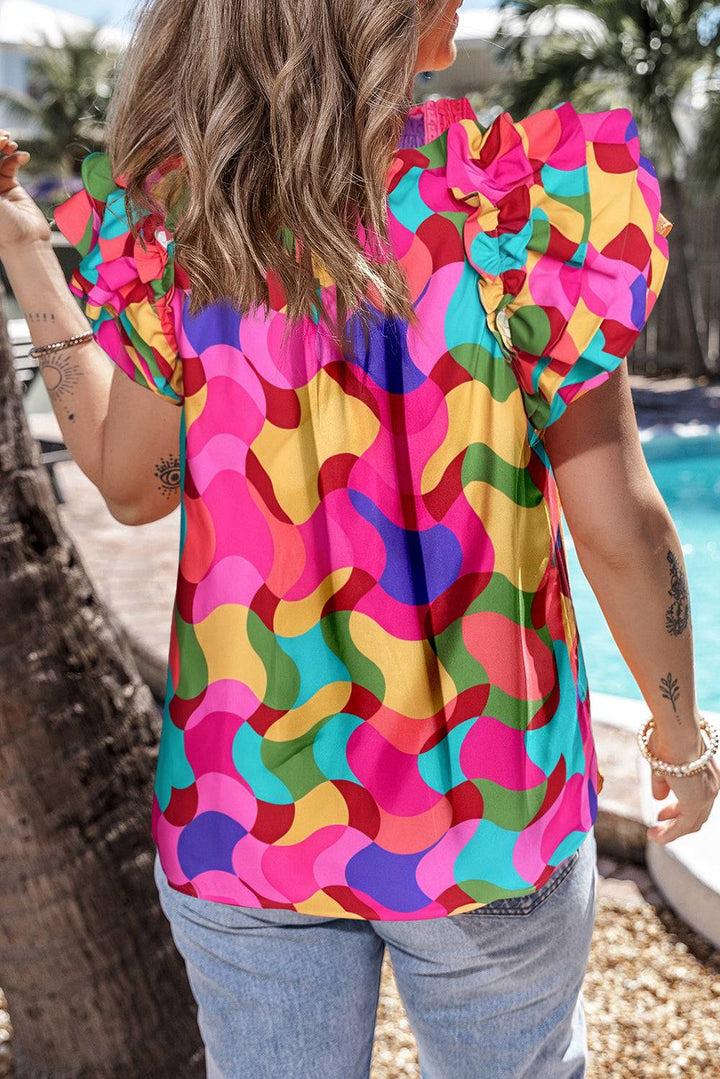 a woman standing next to a pool wearing a colorful top