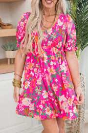 a woman wearing a bright pink floral dress