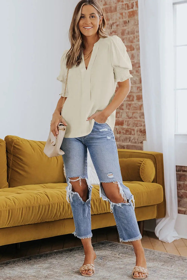 a woman wearing ripped jeans and a white blouse