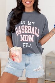 a woman in a baseball mom shirt holding a drink and popcorn