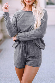 a blonde woman wearing a grey rom and shorts