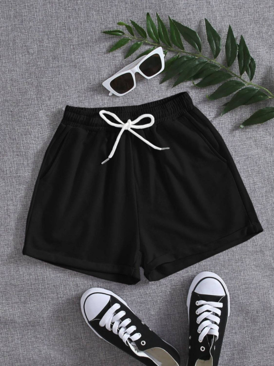 a pair of sneakers, sunglasses and a pair of black shorts