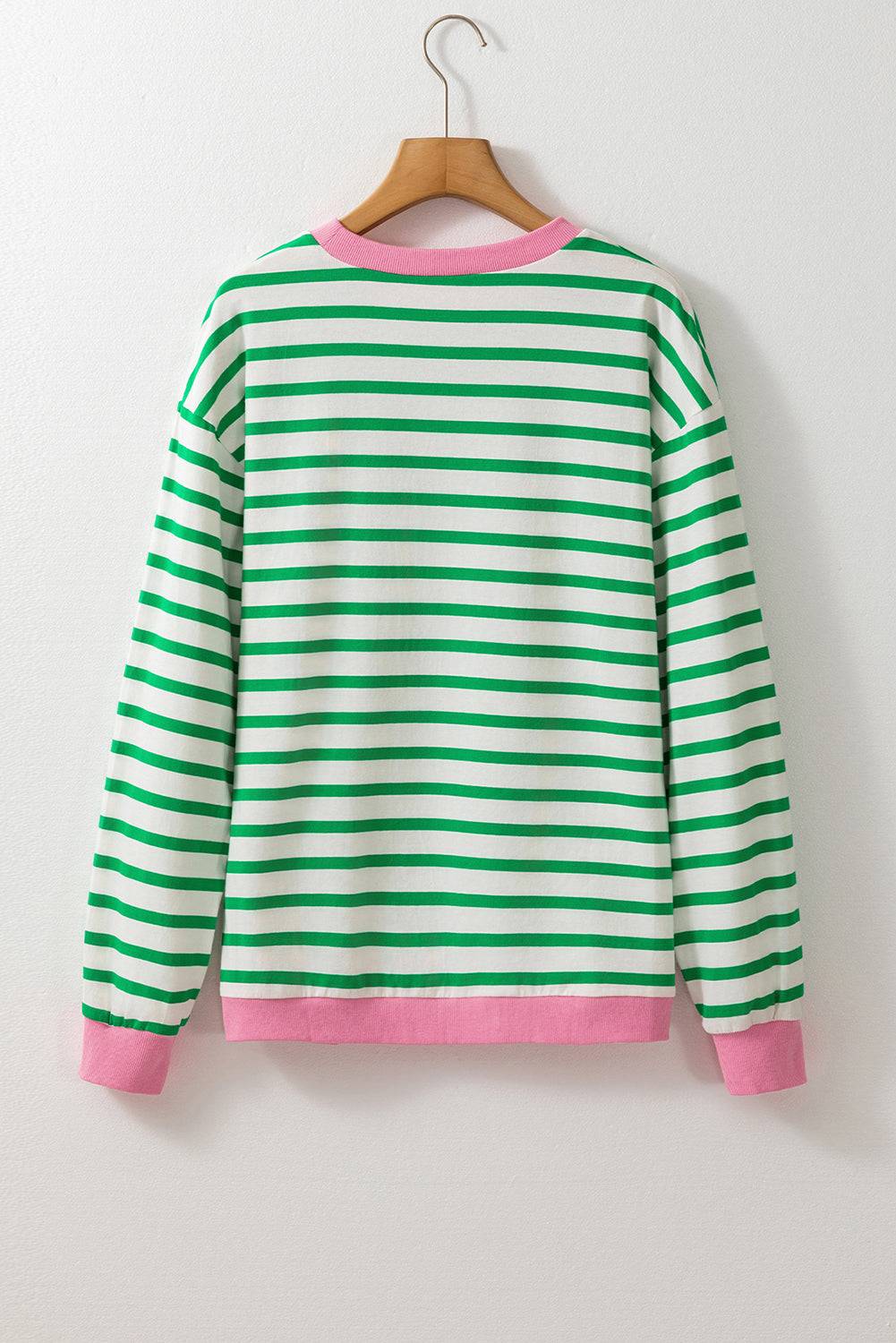 a green and pink striped sweater hanging on a hanger