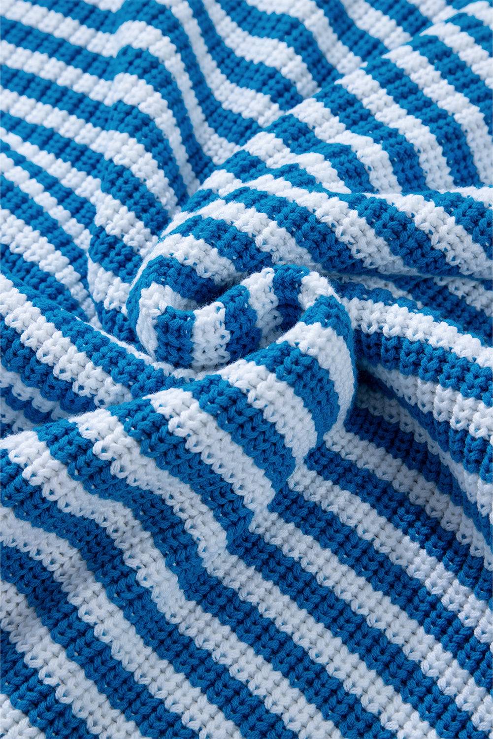 a blue and white striped blanket laying on top of a bed