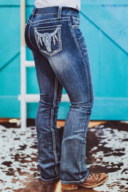 a woman in jeans standing in front of a blue wall