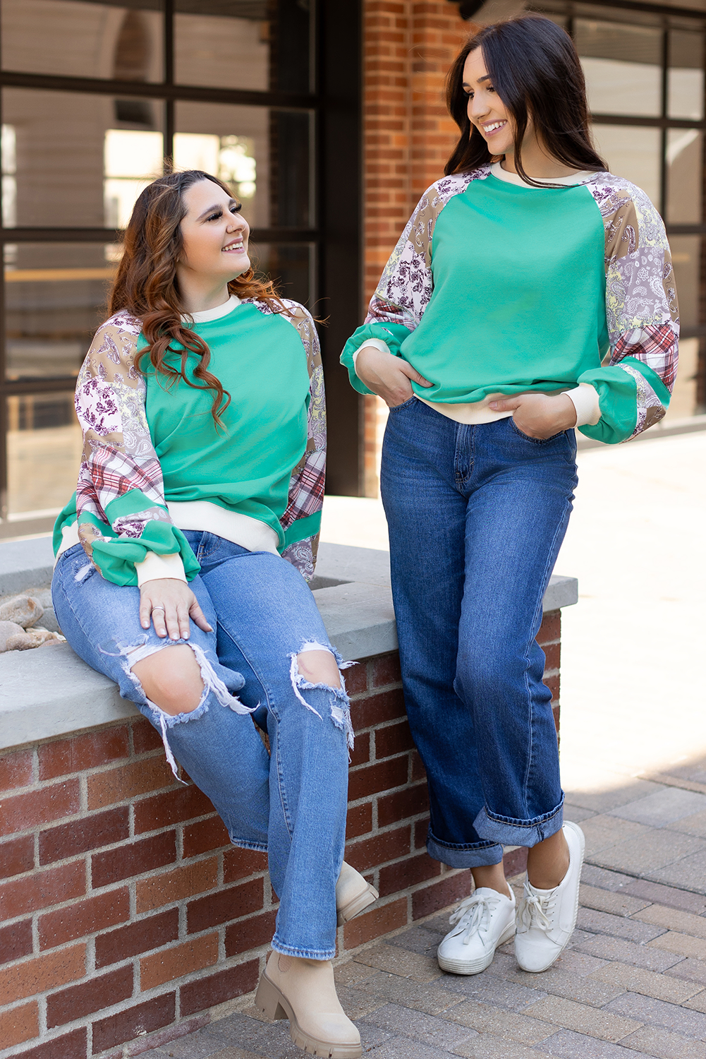 Two women wearing Aruba Blue Plaid Vintage Paisley Patchwork Long Sleeve Raglan Tops in casual outdoor setting. Shop at Faith & Co. Boutique.