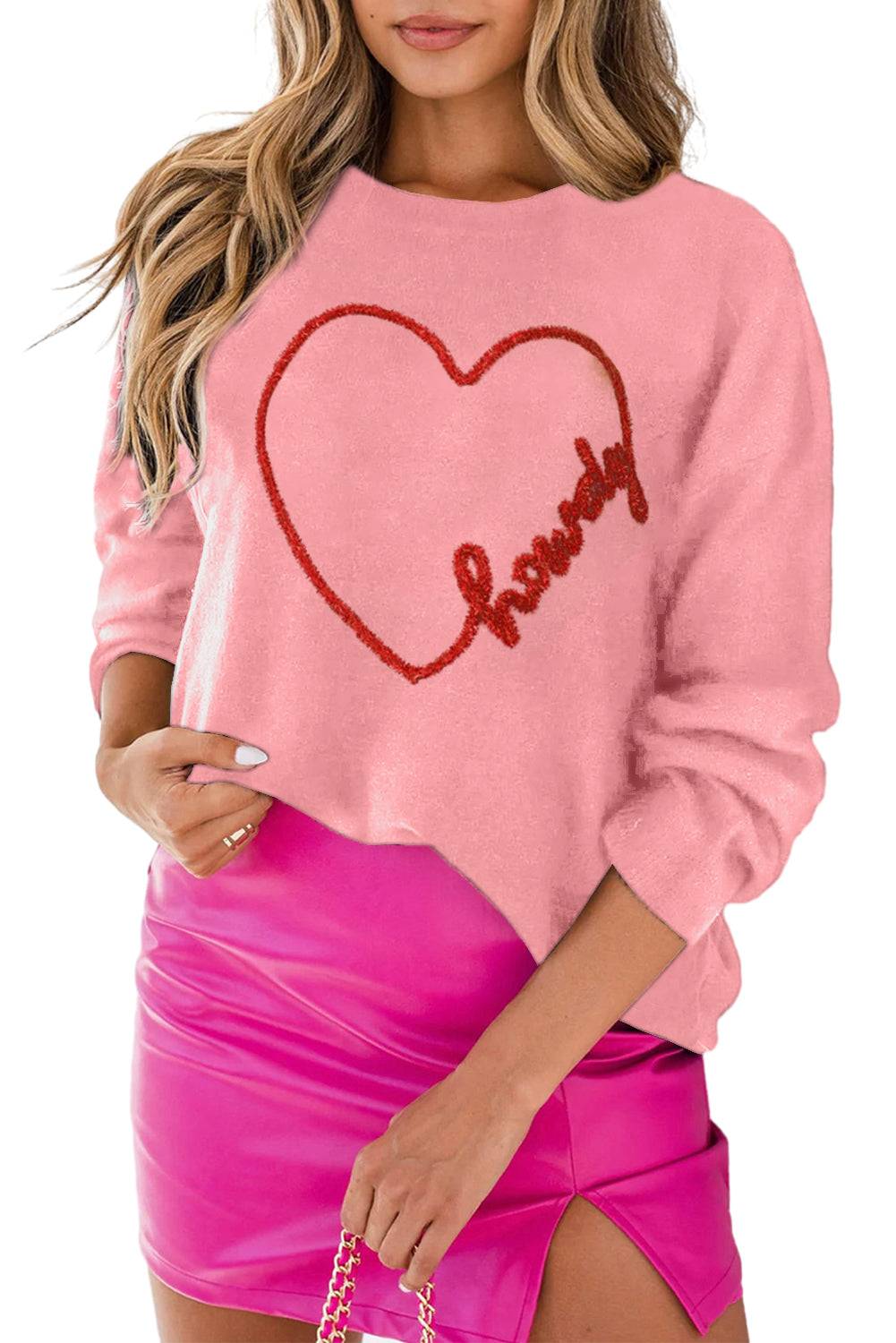 a woman wearing a pink sweater with a heart on it