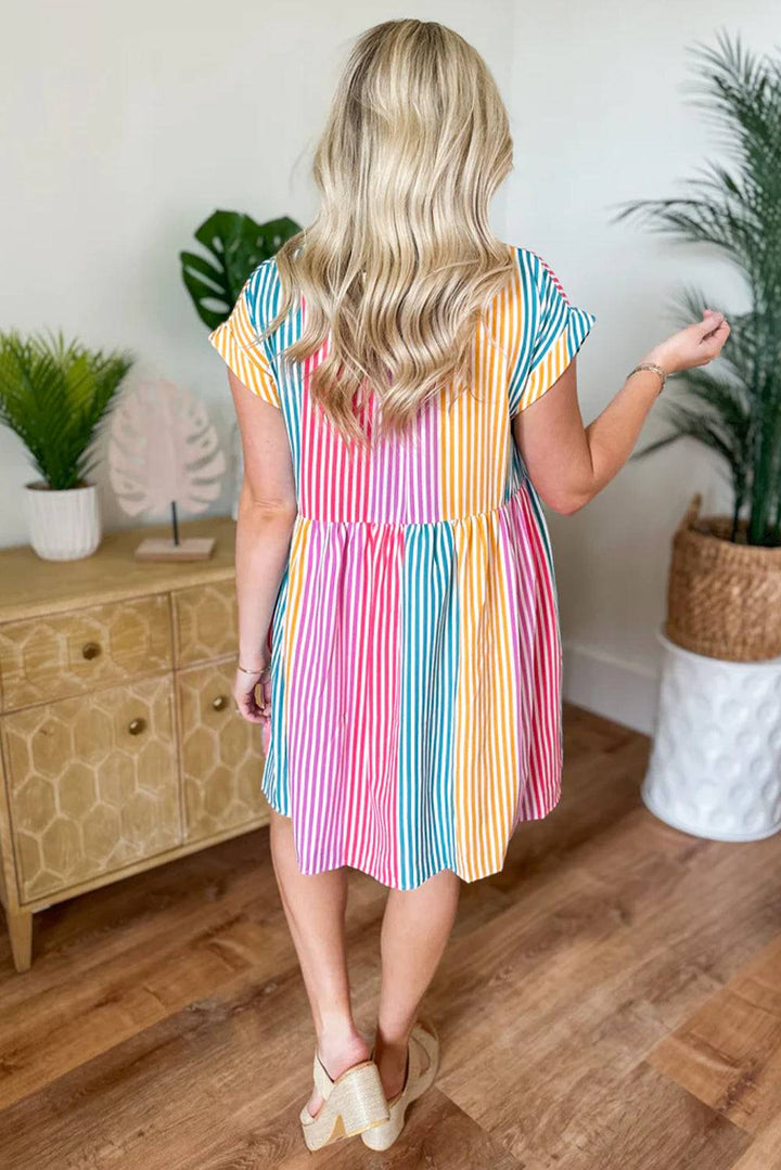 a woman standing in a room wearing a colorful striped dress