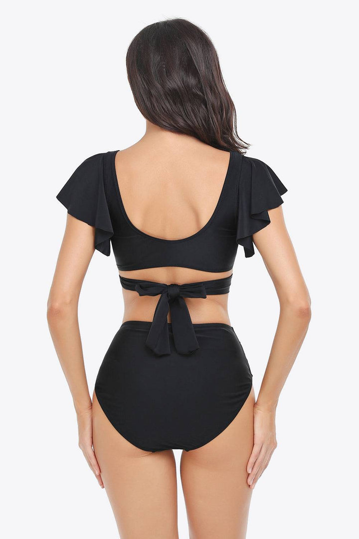 a woman wearing a black bikinisuit with a bow at the back
