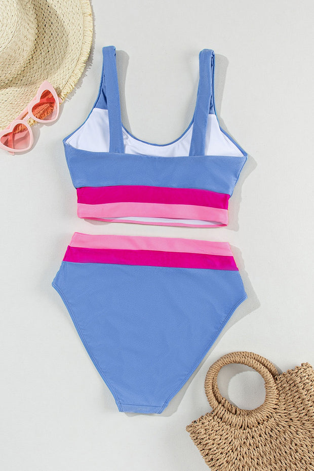 a blue and pink one piece swimsuit next to a straw bag