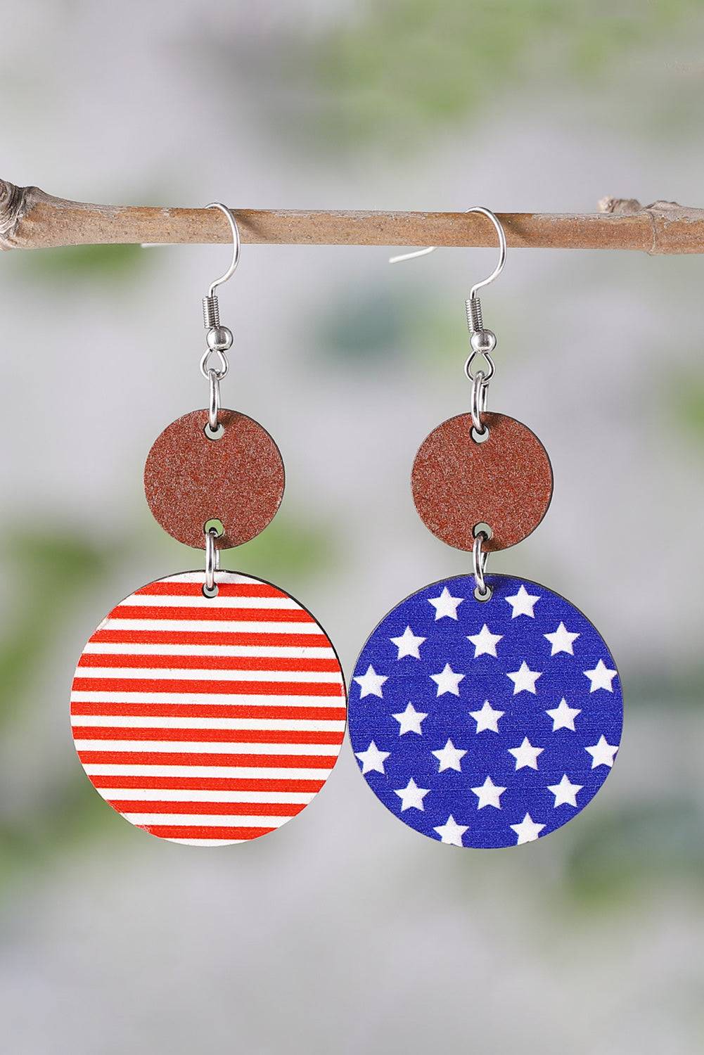 a pair of red, white and blue earrings hanging from a tree branch