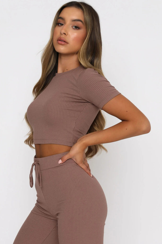 a woman wearing a brown crop top and pants