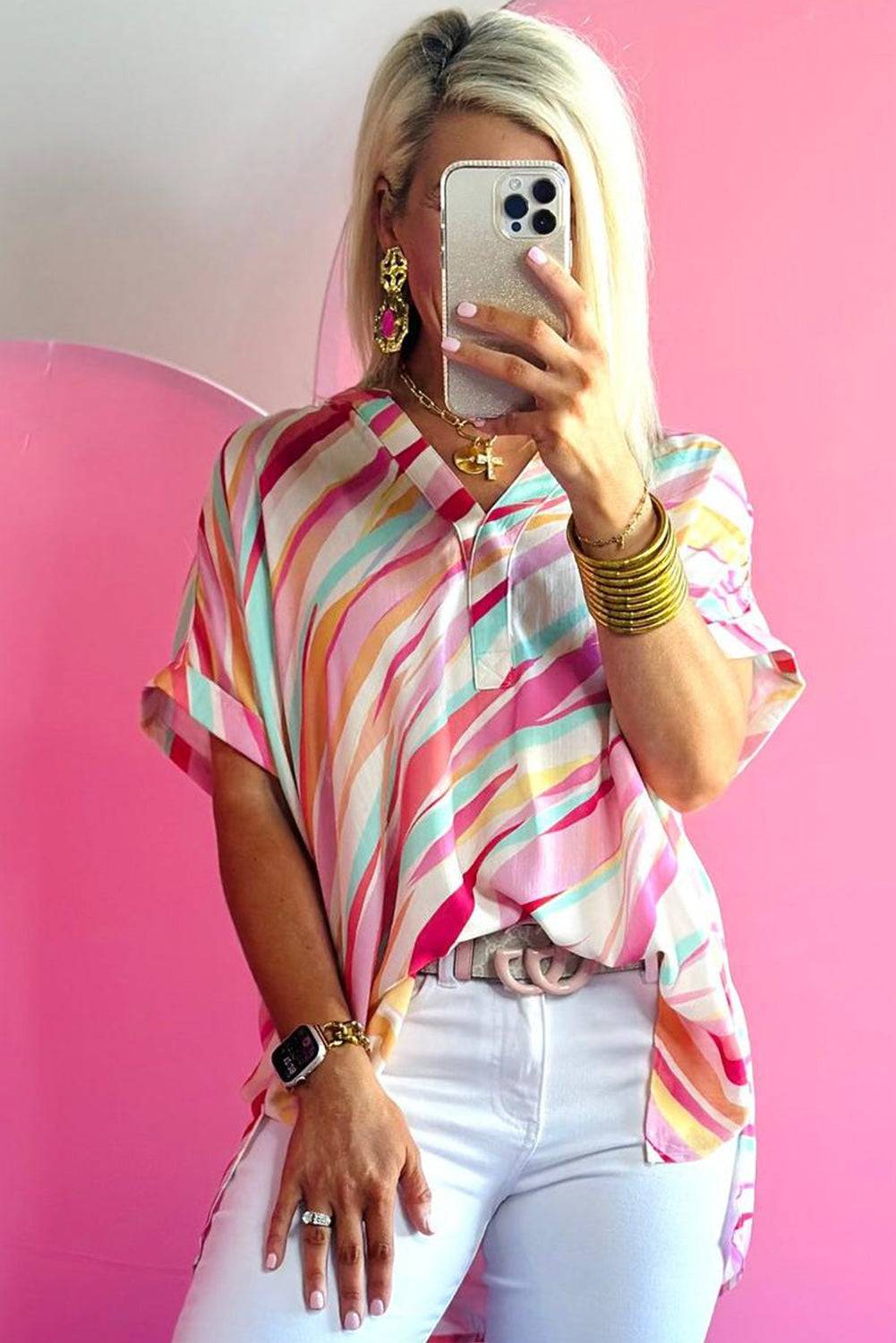 a woman taking a selfie in front of a pink wall