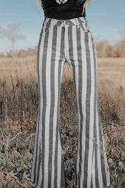 a woman standing in a field wearing striped pants