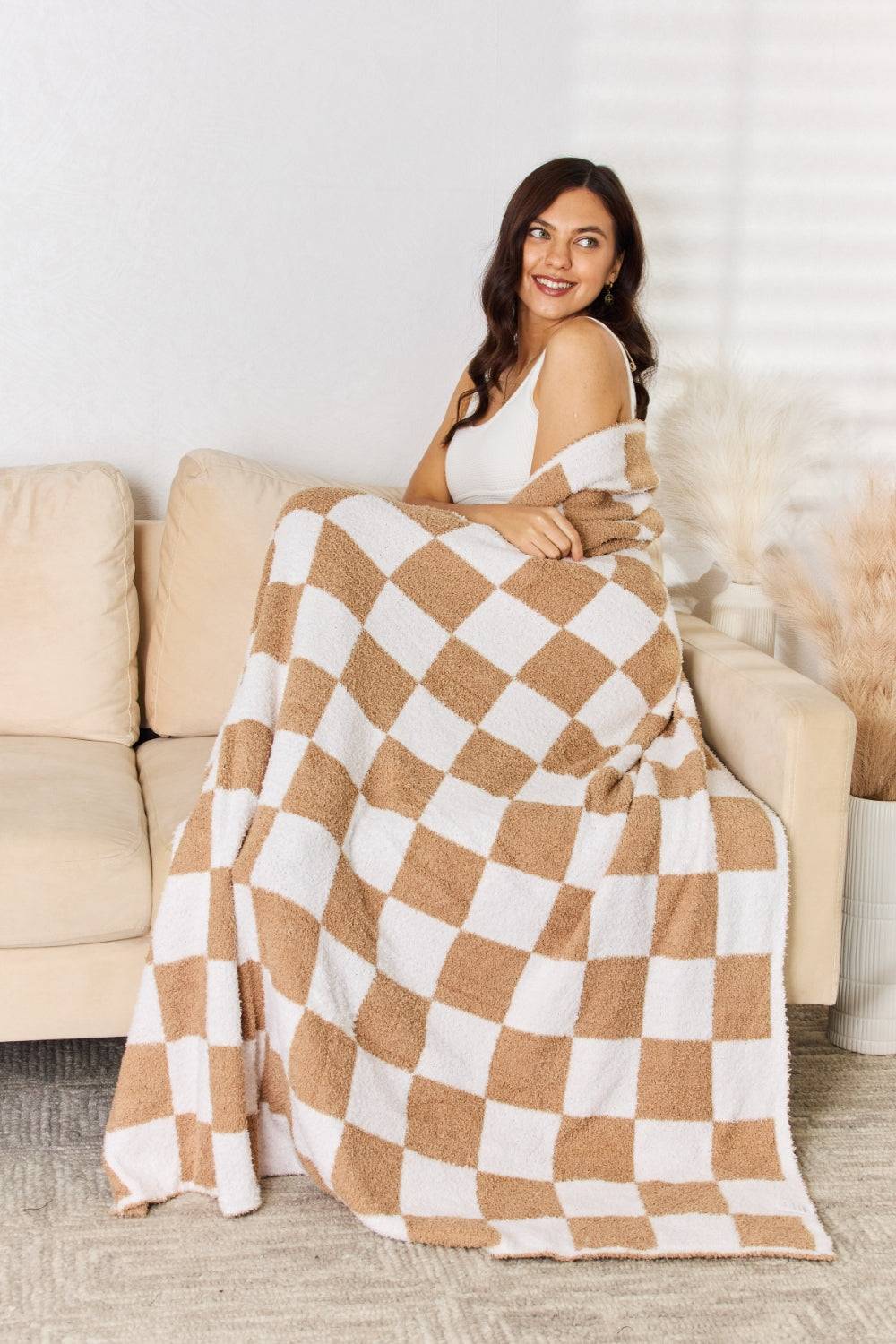 a woman sitting on a couch under a blanket