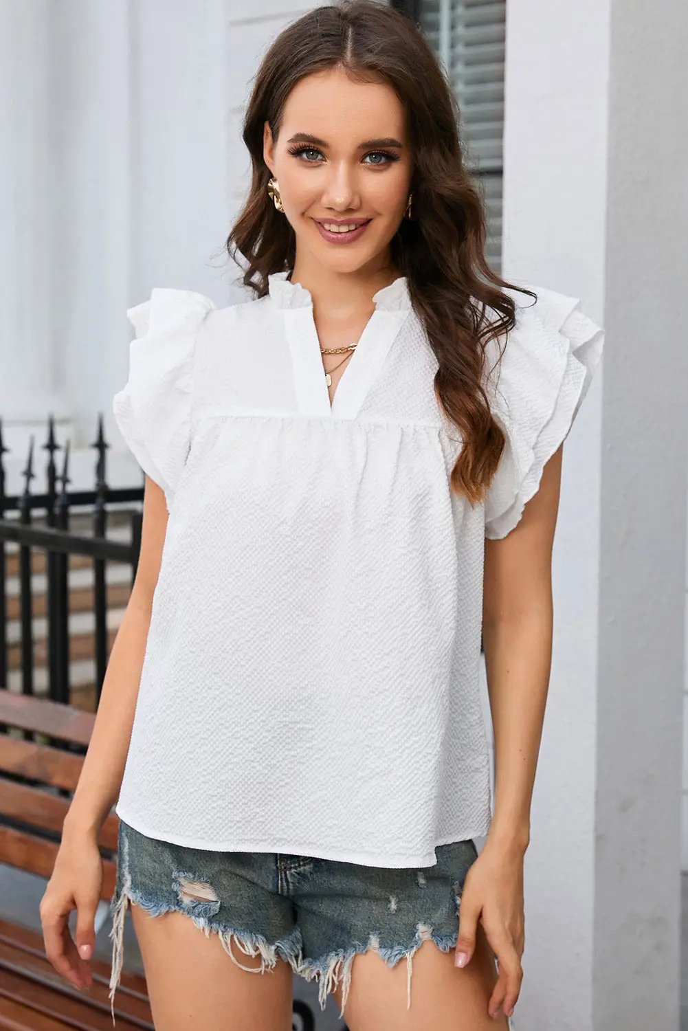 a woman wearing a white blouse and ripped shorts