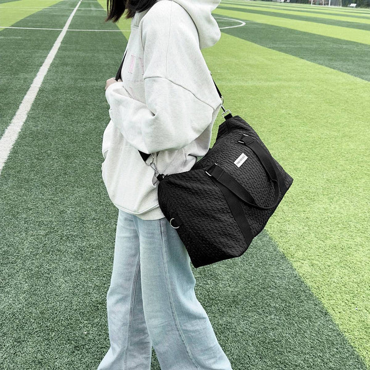 a woman carrying a black bag on top of a field