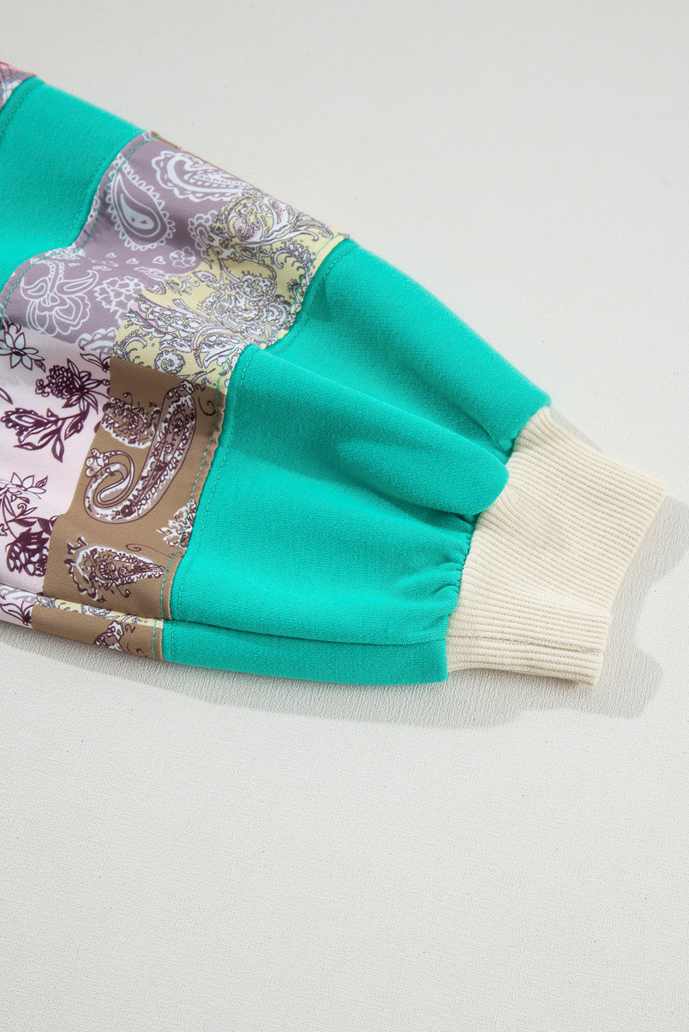 Close-up of patchwork sleeve with paisley and plaid prints on Aruba Blue Raglan Top. Shop at Faith & Co. Boutique.