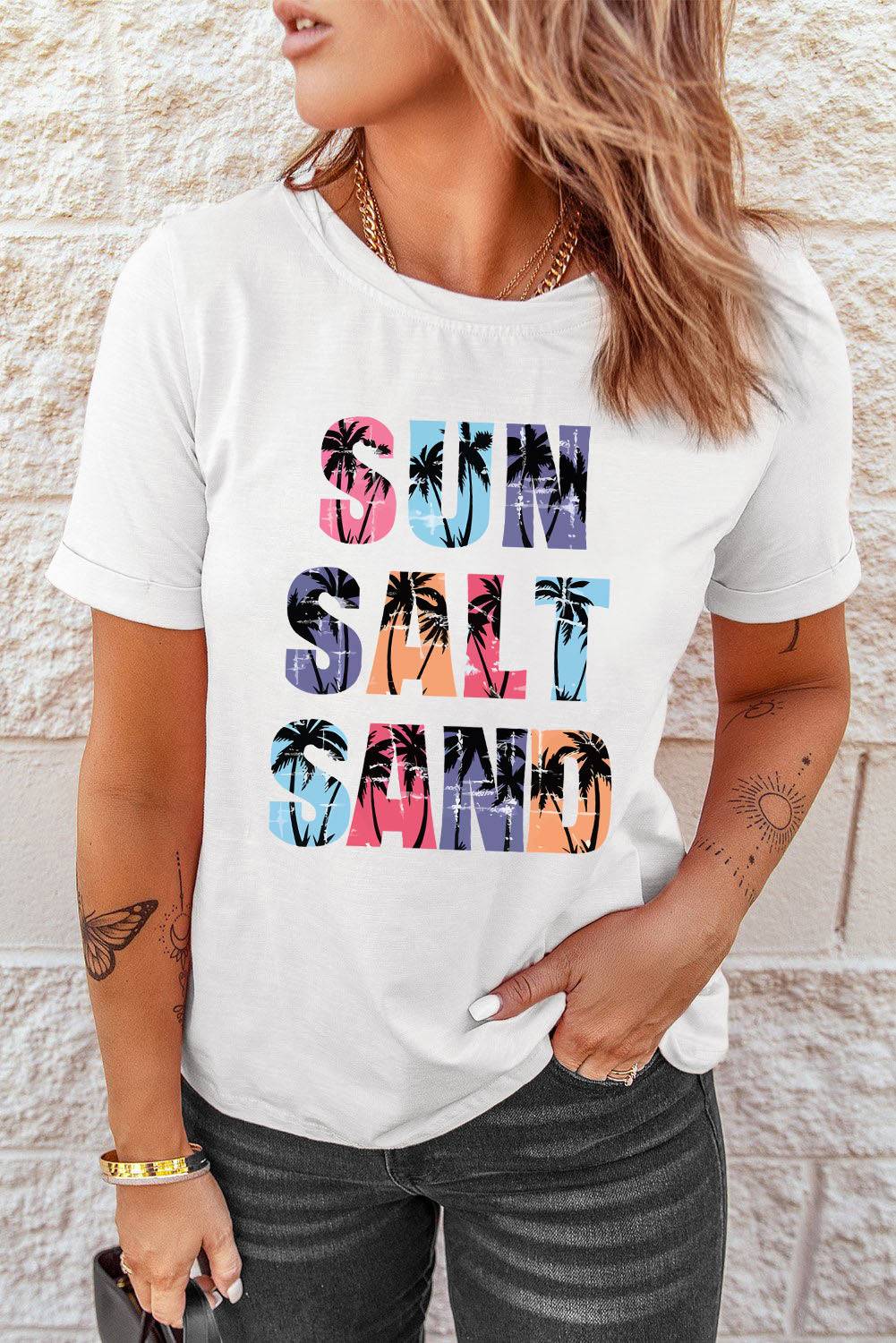 a woman wearing a white t - shirt with the words sun sand and palm trees