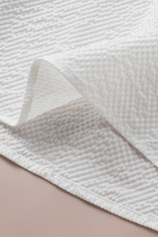 a close up of a white blanket on a bed