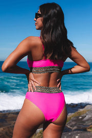 a woman in a pink bikini standing on the beach