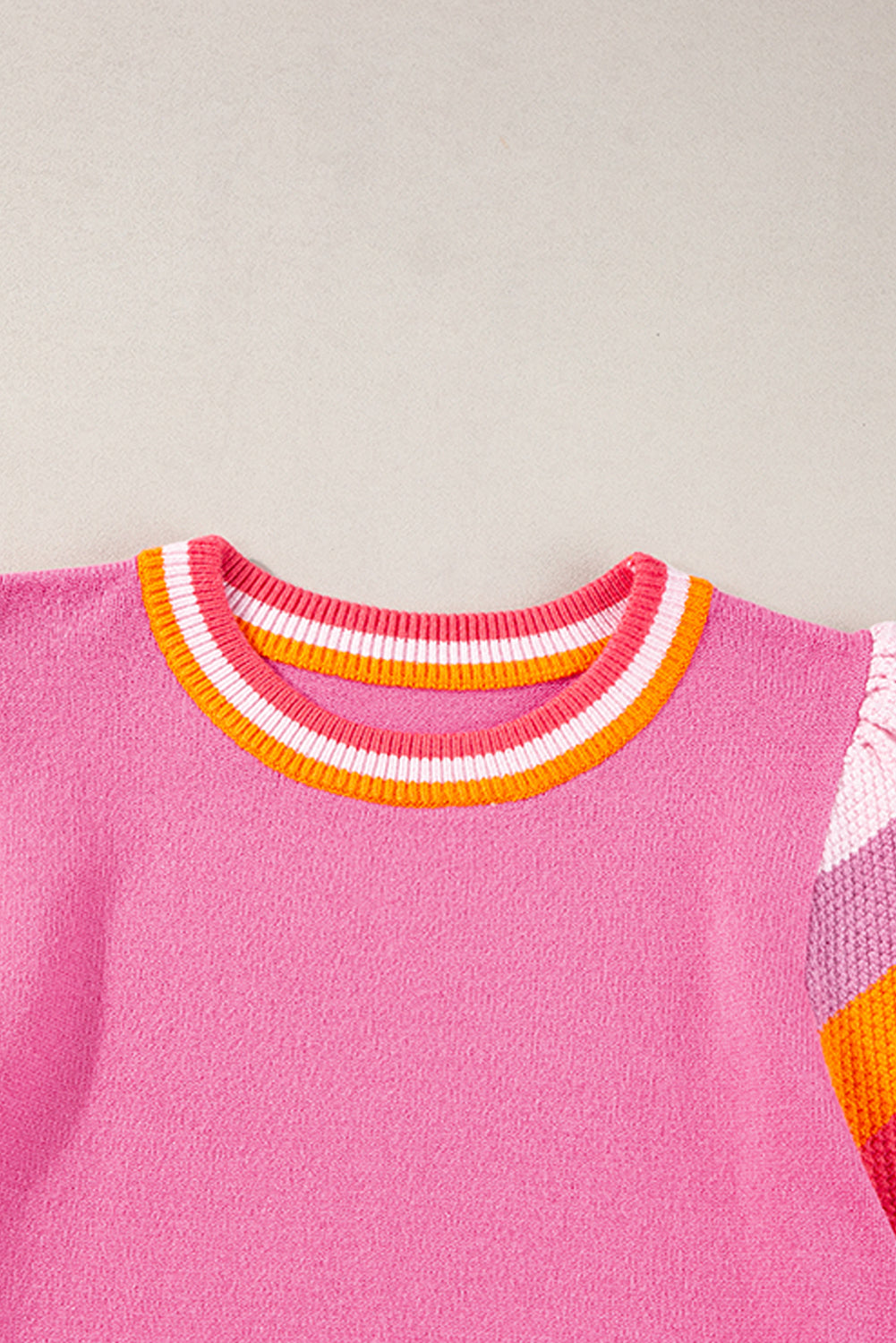 a pink sweater with a multi - colored stripe on the sleeves