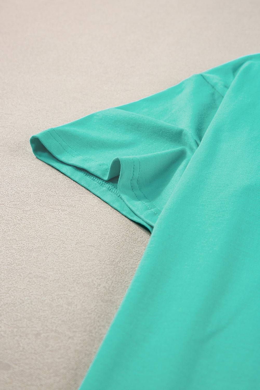 a close up of a green shirt laying on a bed