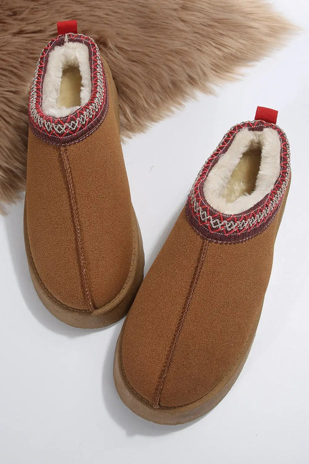 a pair of brown slippers sitting on top of a fur rug