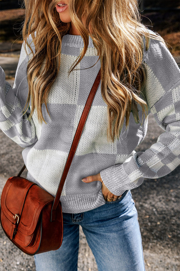 a woman wearing a gray and white sweater holding a brown purse