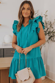 a woman in a blue dress holding a white purse