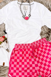 a white shirt and pink checkered shorts on a fur rug