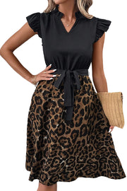 a woman wearing a black top and leopard print skirt