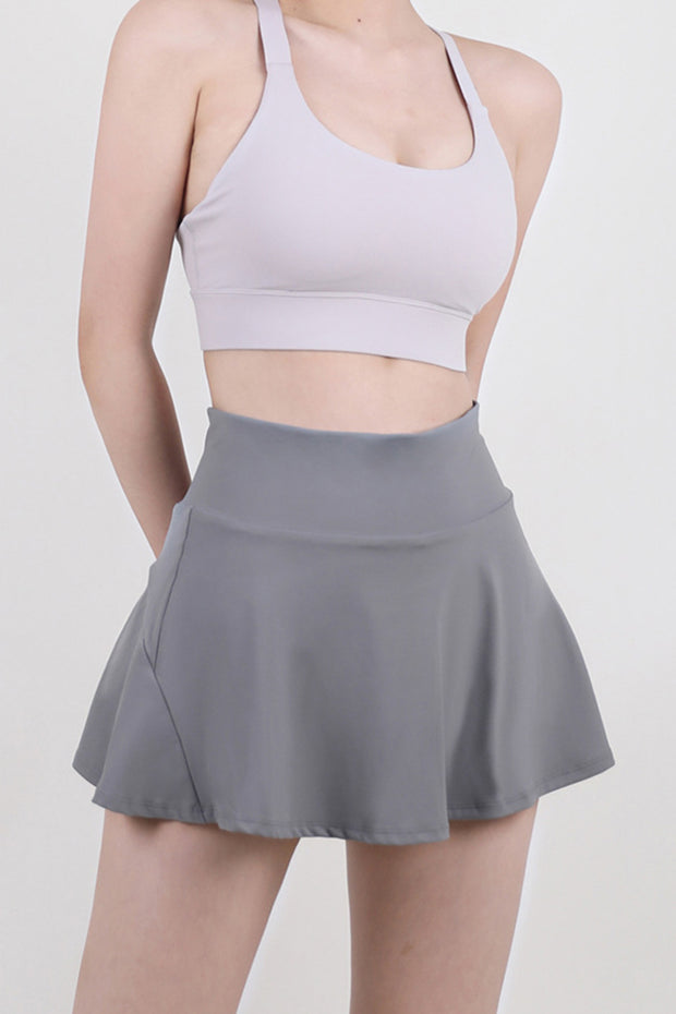 a woman in a gray sports bra top and a gray skirt
