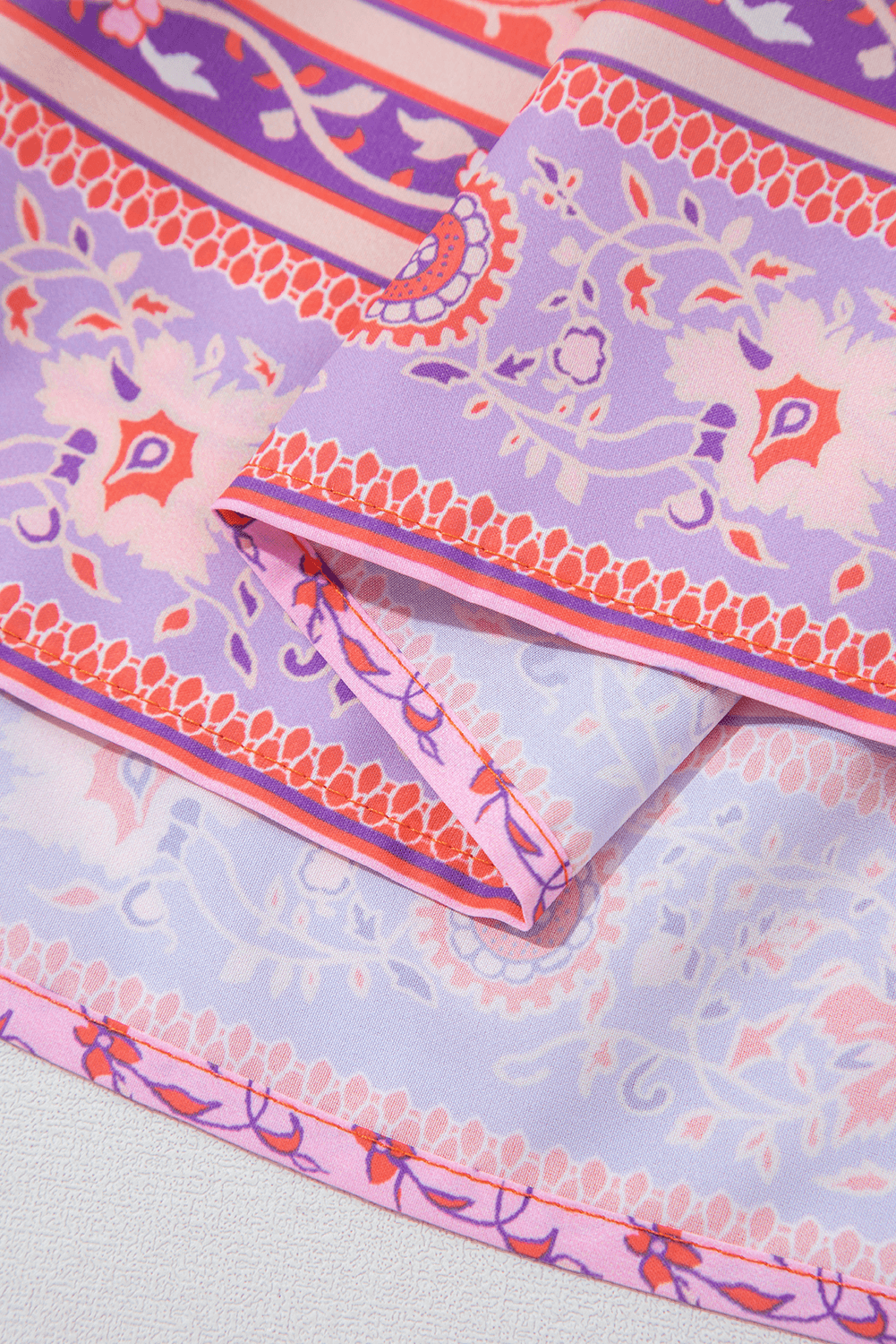 hem detail of Red Floral Print Tasseled Tied Sleeve Empire Waist Maxi Dress, showing layered purple and red floral border print