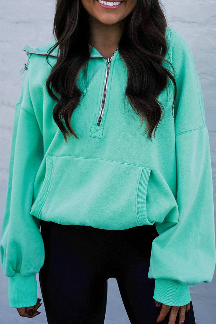 a woman wearing a green sweatshirt and black pants