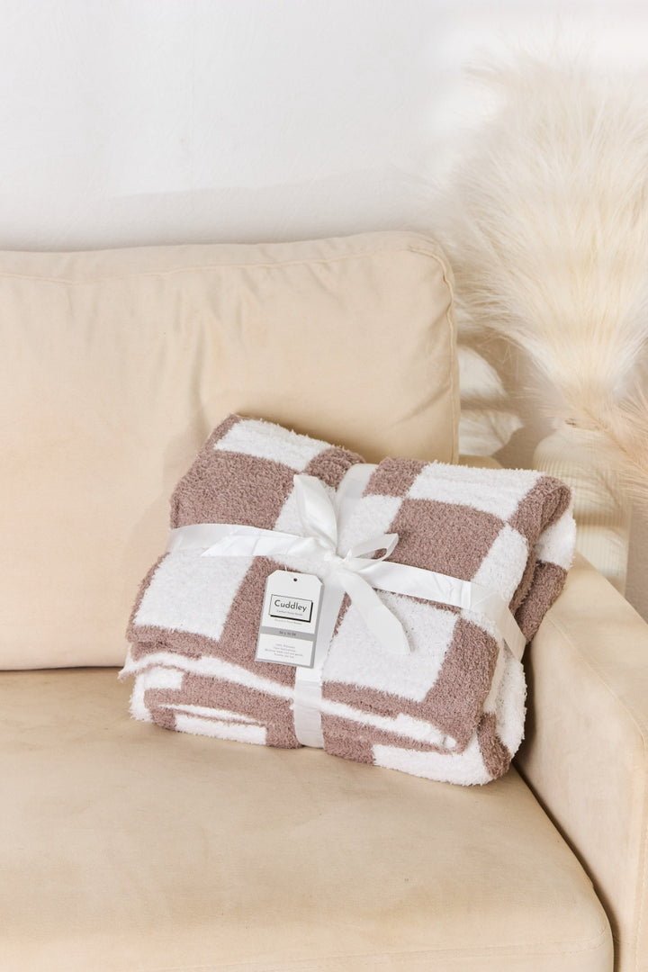 a brown and white blanket sitting on top of a couch