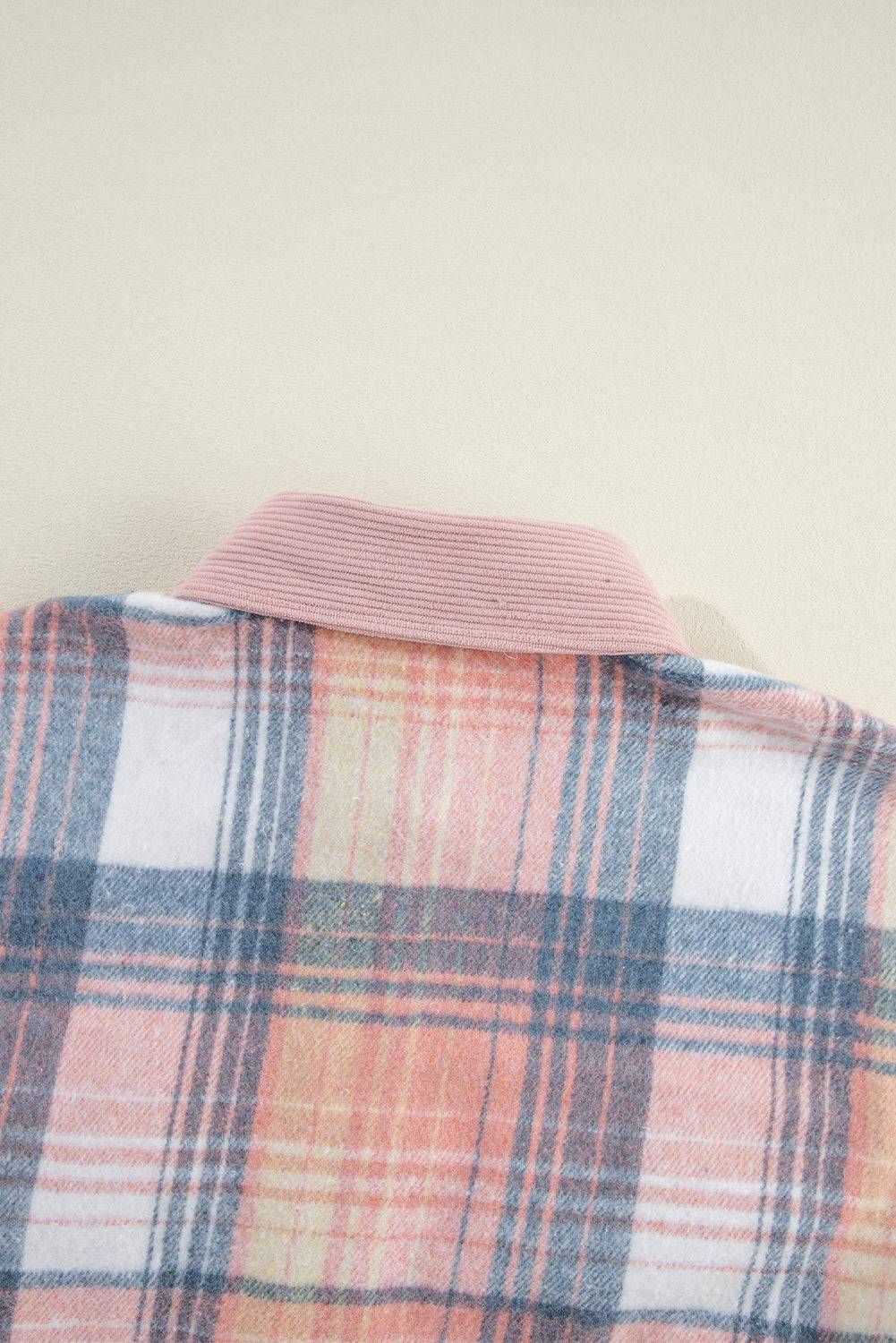 a pink and blue plaid jacket hanging on a wall