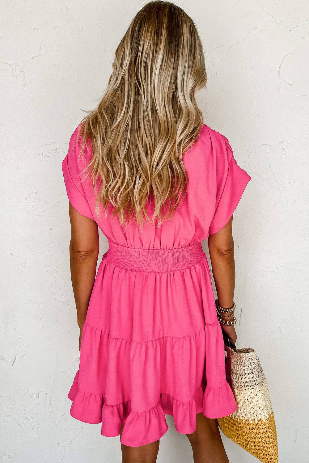 a woman in a pink dress holding a straw hat