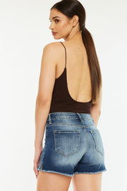 a woman in a black tank top and denim shorts
