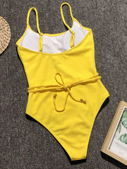a yellow and white one piece swimsuit next to a book