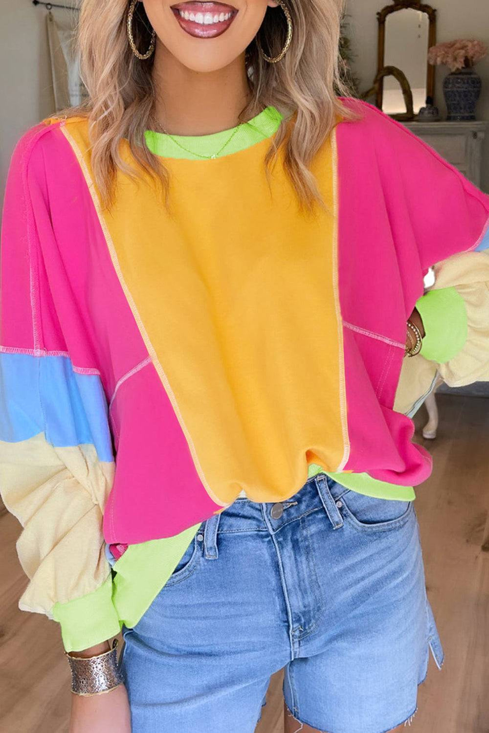a woman wearing a colorful top and denim shorts