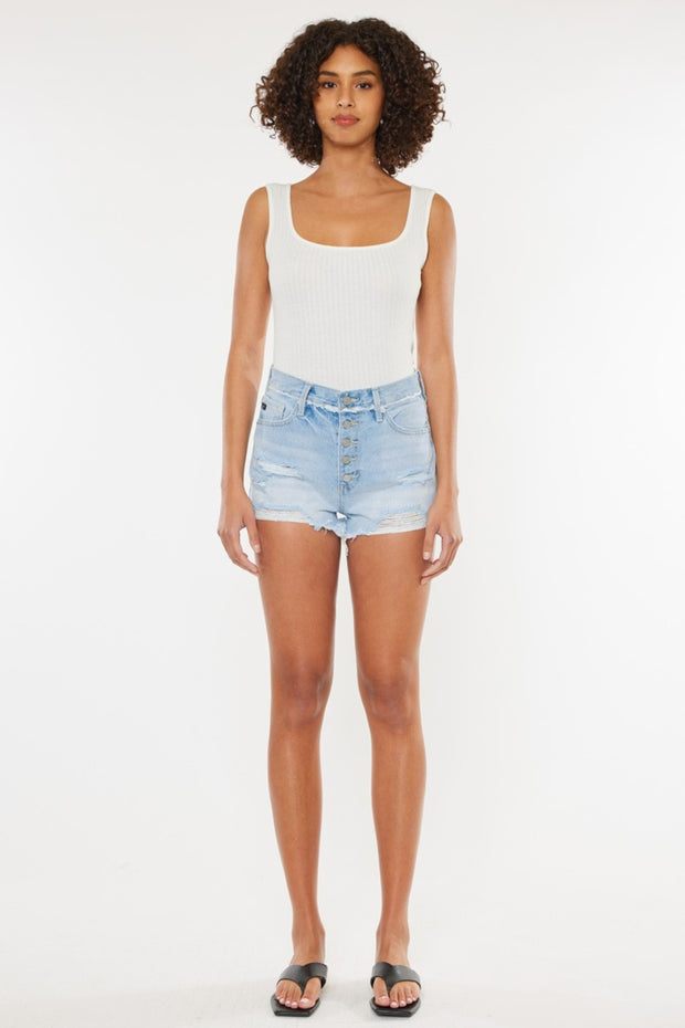 a woman in a white tank top and denim shorts