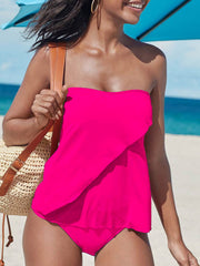 a woman in a pink swimsuit walking on the beach