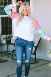 a woman wearing ripped jeans and a white top