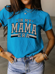 a woman wearing a blue shirt that says in my mama era