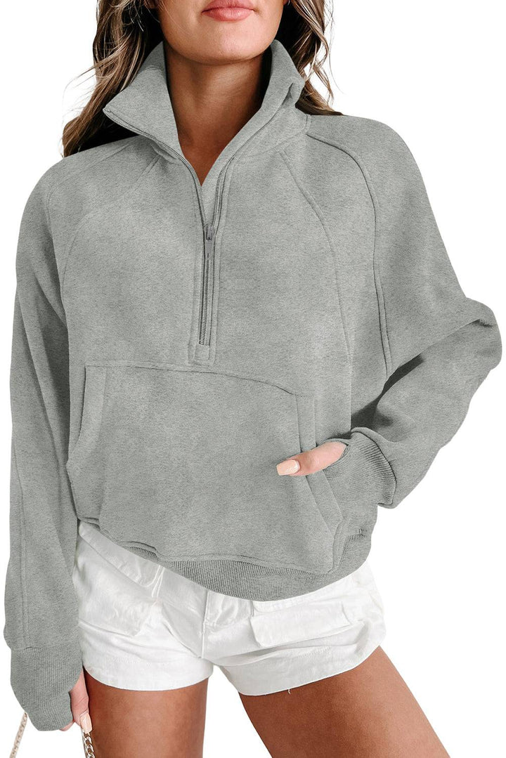 a woman wearing a gray sweatshirt and white shorts