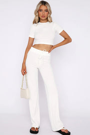 a woman wearing white pants and a crop top