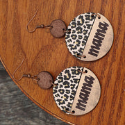 a pair of leopard print earrings sitting on top of a wooden table