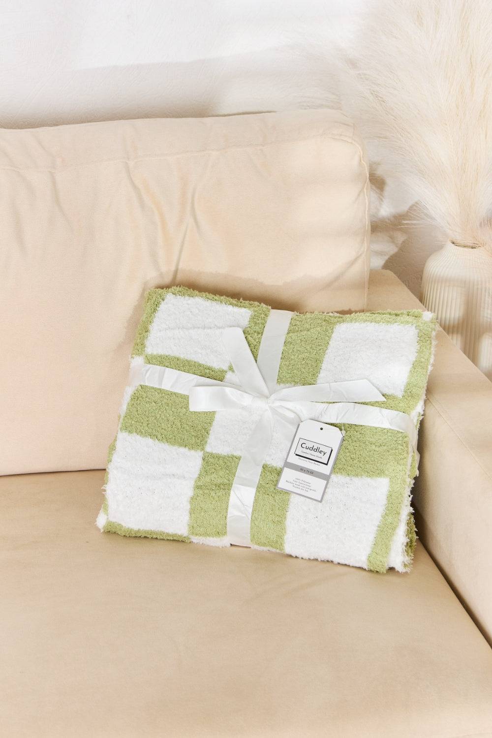 a green and white blanket sitting on top of a couch